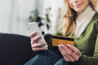 smartphone ve kredi kartı elinde tutan kadın görünümünü kırpılmış