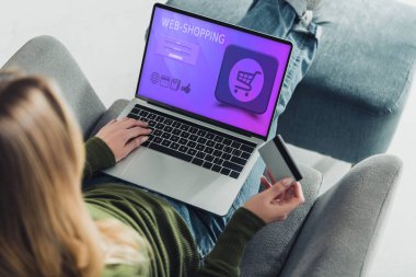 kredi kartı tutan ve ekran web sitesinde alışveriş web ile dizüstü bilgisayar kullanarak bir kadın görünümünü kırpılmış 