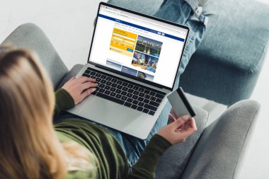 kredi kartı tutan ve rezervasyon web sitesinde ekran ile dizüstü bilgisayar kullanarak bir kadın görünümünü kırpılmış 