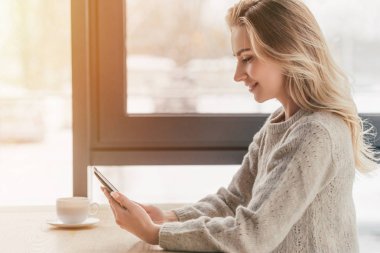 e-okuyucu fincan kahve tutan neşeli kadın