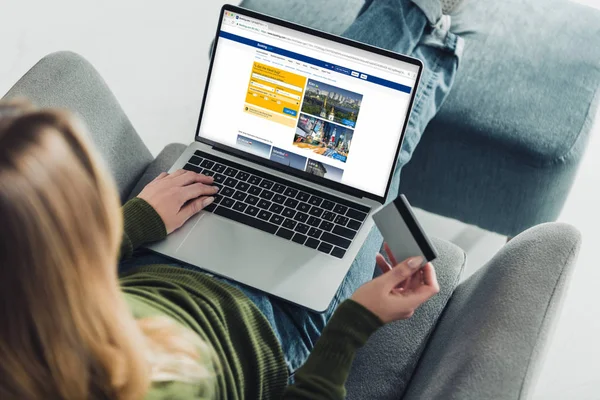 kredi kartı tutan ve rezervasyon web sitesinde ekran ile dizüstü bilgisayar kullanarak bir kadın görünümünü kırpılmış 