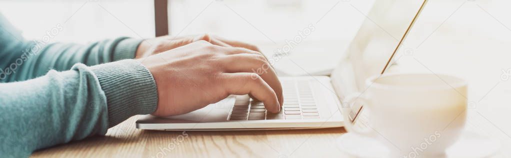 cropped view of man typing on laptop while working at home