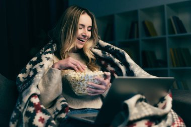 mutlu laptop film izlerken ve patlamış mısır ile kase tutarak