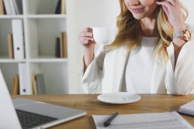 Kırpılan Kupası içkiyle tutan neşeli kadın görünümünü 