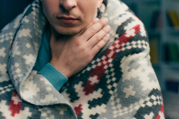 cropped view of man wrapped in blanket having sore throat 