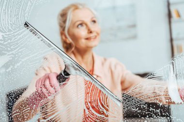 Gülümseyen kadın kıdemli temizlik pencere cam silecek ile