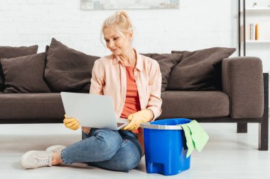 Evi temizlerken laptop ile poz lastik eldiven meraklı kadın kıdemli