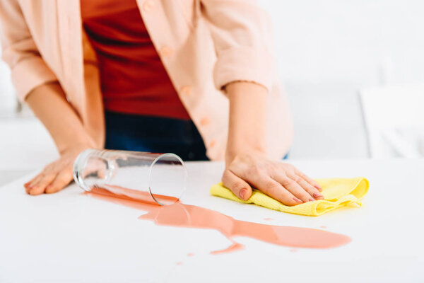 Частичный вид женщины, вытирающей пятна от вина тряпкой
