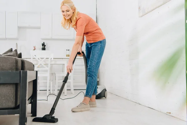 幸せな先輩女掃除機で床を掃除 — ストック写真