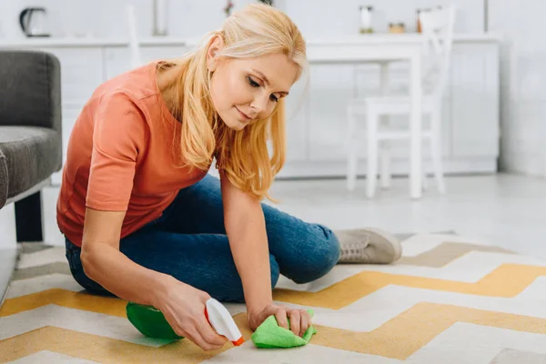 Koncentrerad Blond Kvinna Rengöring Randig Matta Med Spray Och Trasa — Stockfoto