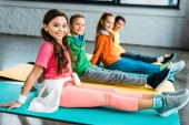 Mosolyogva ül fitness szőnyeg elegáns gyerekek