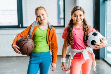 Çocuklarda spor salonunda topları tutan spor giyim gülümseyen