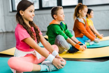 Gülümseyen çocuklar fitness paspaslar üzerinde jimnastik egzersizleri yapıyor
