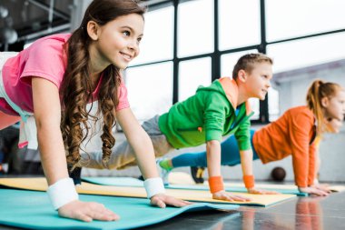 Gülümseyen çocuklar tahta yapıyor egzersiz fitness paspaslar üzerine
