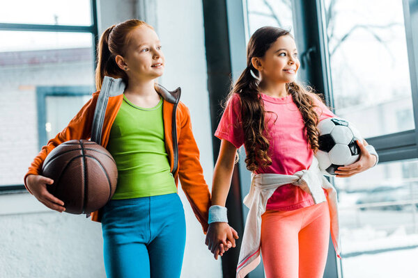 Blissful kids holding hands while posing in gym