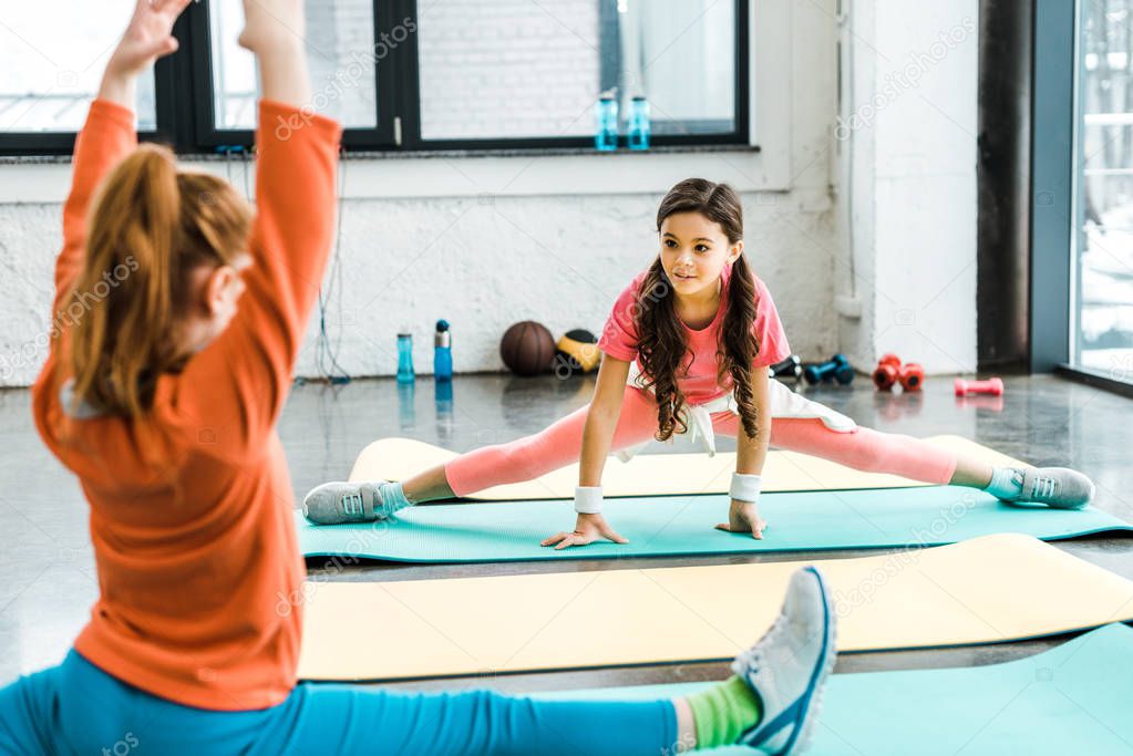Preteen children doing twine on mats in gym