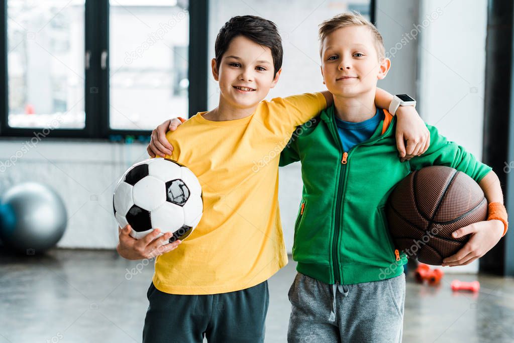 Pleased boys embracing while posing with balls