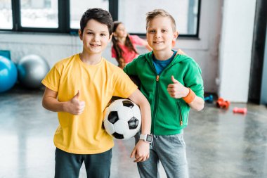 Boys with soccer ball posing with thumbs up clipart