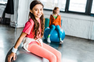 Uzun saçlı pembe spor fitness topu üzerinde oturan çocukta