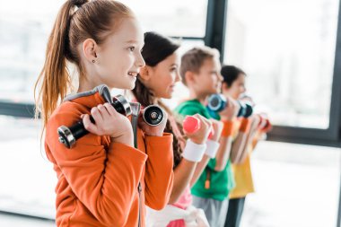 Spor eğitimi dumbbells ile gülümseyen çocuklar