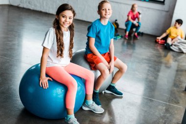 Fitness topları üzerinde oturan ve kameraya seyir varoluş çocuklar