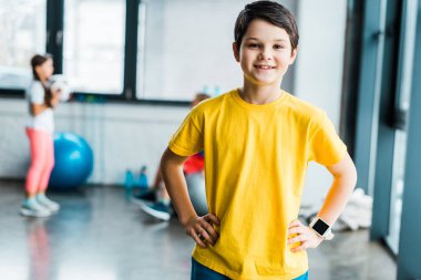 Silah spor salonunda akimbo ile poz gülümseyen esmer çocuk