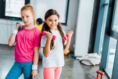 Şirin çocuklar spor salonunda dumbbells ile poz