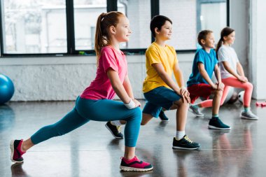 Neşeli çocuklar spor salonunda germe yapıyor grup