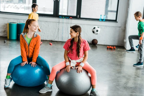 Fitness topları üzerinde otururken konuşan çocuklar