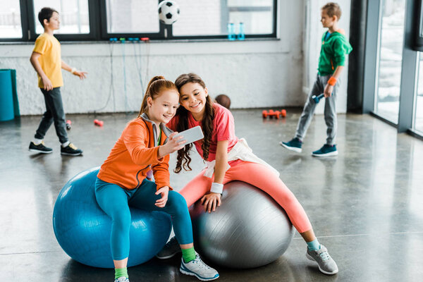 Kids taking selfie on fitness balls in gym