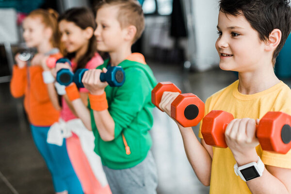Cute children training with colorful dumbbells