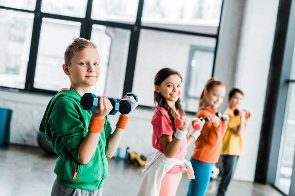 Cute children with dumbbells looking at camera