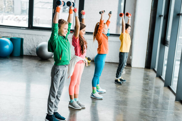 Group of kids with dumbbells holding hands up