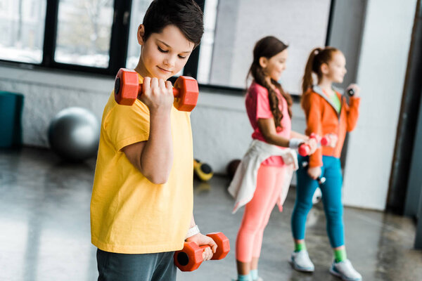 Preteen kids training with dumbbells in gym