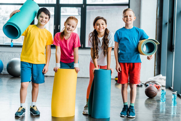 Группа детей, позирующих в тренажерном зале с тренажерами
