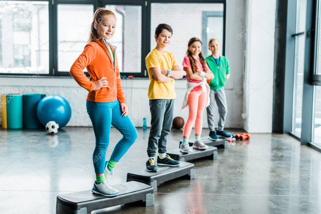 Adorable kids standing on step platforms in gym
