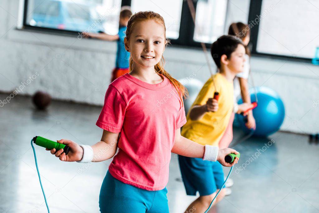 Preteen kids jumping with skipping ropes in gym
