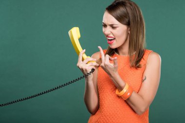 Retro telefon bağırıyor ve orta parmak yeşil izole gösterilen güzel kızgın kadın