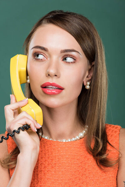 красивая стильная женщина смотрит в сторону и говорить по ретро-телефону изолированы на зеленый

