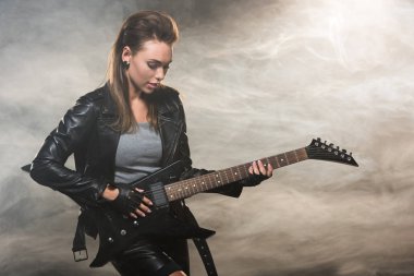 elektro gitar çalmak dumanlı arka plan üzerinde deri ceketli güzel kadın