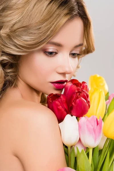 在灰色隔离的五颜六色的郁金香花束的温柔的裸体春天的女人 — 图库照片