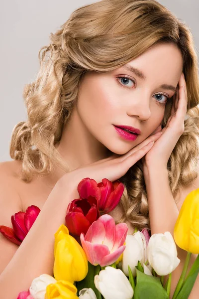 年轻的裸体迷人的春天的女人摆姿势与五颜六色的郁金香花束隔离在灰色 — 图库照片
