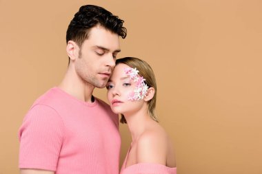 yakışıklı adam çiçekli bej üzerinde izole yüzünde güzel kadınla ayakta 