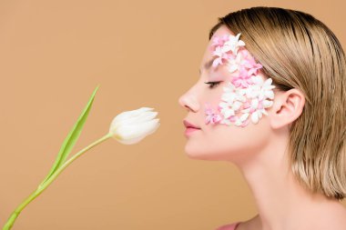 Yüzündeki üzerinde bej izole lale kokulu çiçekler ile zarif kadın yan görünüm