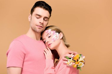çiçekli yakışıklı adam yandan kucaklayan kadın üzerinde bej izole 