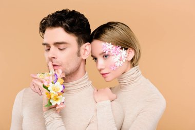 çekici kız arkadaşıyla ayakta ve bej izole hush işaret gösteren bir adam