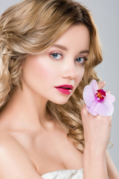 young elegant beautiful woman holding purple orchid on hand isolated on grey