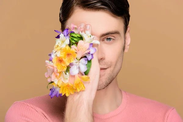 Hombre Sonriente Cubriendo Ojo Con Flores Alstroemeria Mano Aisladas Beige —  Fotos de Stock