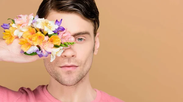 严重的人覆盖一只眼睛与鲜花在手上孤立的米色 — 图库照片