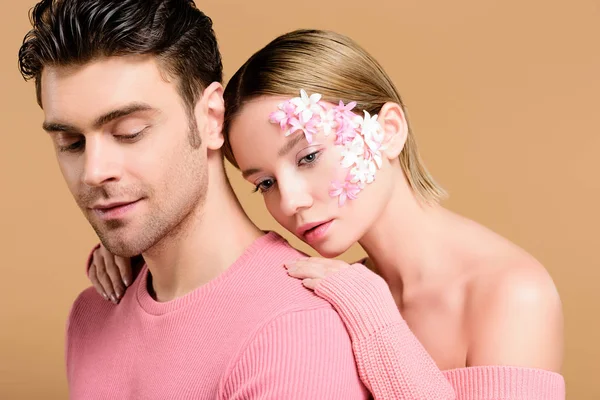 ベージュに分離された男を抱いて顔に花をつける魅力的な女性 — ストック写真